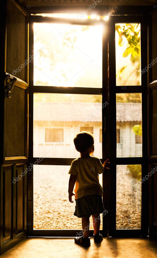 Backlit toddler standing in front of door