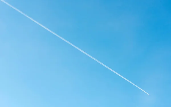 Aereo jet che vola e la sua contrail su cielo blu — Foto Stock