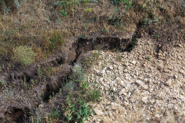 Катастрофа горного оползня в особо опасной местности. Большие трещины в земле, спуск больших слоев земли, блокирующих дорогу. Смертельная опасность запруды людей у подножия горных склонов
