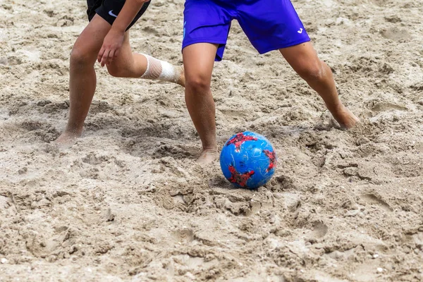 Garoto Joga Bola De Futebol Na Praia Arenosa. Pés Descalços De