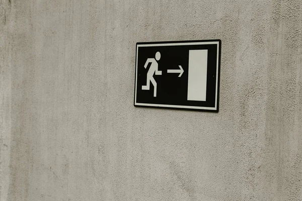 Green emergency exit sign (fire exit, emergency exit, evacuation strip, fire extinguisher) on the wall of the stands of the stadium