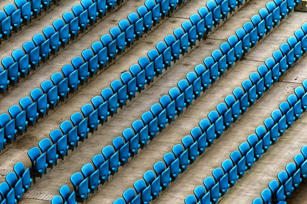 Blank old plastic chairs at the stadium. Number of empty seats in a small old stadium. Scratched worn plastic seats for fans