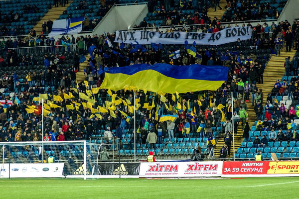 ODESSA, UKRAINE - March 24, 2016: Football fans and spectators in the stands of the stadium emotionally support their team during the match of the national team of Ukraine and Cyprus. Emotions, torches, smoke, cries