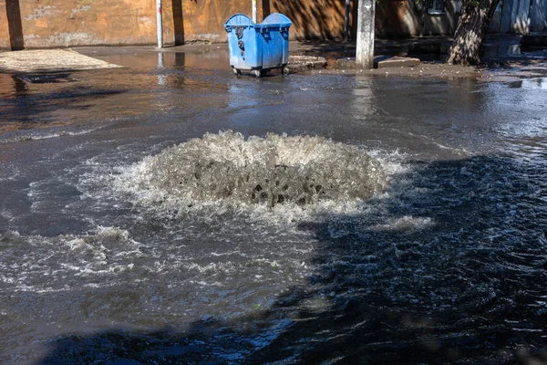 水は道路下水のハッチから流れます 下水の排水噴水 下水システムの事故 汚れた下水は道路上の噴水を流れる ハッチの噴水から水が流れる — ストック写真