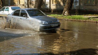 Odessa, Ukrayna -3 Temmuz 2018: yağmur fırtına tarafından neden olduğu sel sırasında su dolu bir yolda araba sürmek. Arabalar sokaklarda sel su üzerinde yüzer. Sıçramak üstünde belgili tanımlık makine. Büyük bir su birikintisi olan sular altında şehir yol