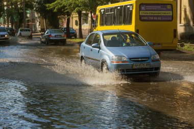 Odessa, Ukrayna -3 Temmuz 2018: yağmur fırtına tarafından neden olduğu sel sırasında su dolu bir yolda araba sürmek. Arabalar sokaklarda sel su üzerinde yüzer. Sıçramak üstünde belgili tanımlık makine. Büyük bir su birikintisi olan sular altında şehir yol