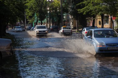 Odessa, Ukrayna -3 Temmuz 2018: yağmur fırtına tarafından neden olduğu sel sırasında su dolu bir yolda araba sürmek. Arabalar sokaklarda sel su üzerinde yüzer. Sıçramak üstünde belgili tanımlık makine. Büyük bir su birikintisi olan sular altında şehir yol
