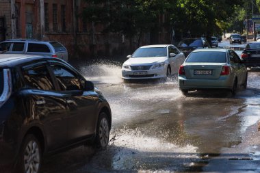 Odessa, Ukrayna -3 Temmuz 2018: yağmur fırtına tarafından neden olduğu sel sırasında su dolu bir yolda araba sürmek. Arabalar sokaklarda sel su üzerinde yüzer. Sıçramak üstünde belgili tanımlık makine. Büyük bir su birikintisi olan sular altında şehir yol