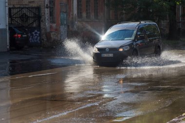 Odessa, Ukrayna -3 Temmuz 2018: yağmur fırtına tarafından neden olduğu sel sırasında su dolu bir yolda araba sürmek. Arabalar sokaklarda sel su üzerinde yüzer. Sıçramak üstünde belgili tanımlık makine. Büyük bir su birikintisi olan sular altında şehir yol