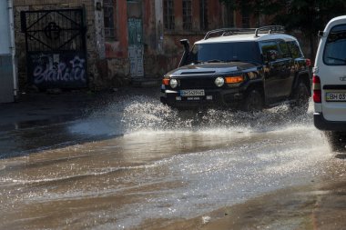 Odessa, Ukrayna -3 Temmuz 2018: yağmur fırtına tarafından neden olduğu sel sırasında su dolu bir yolda araba sürmek. Arabalar sokaklarda sel su üzerinde yüzer. Sıçramak üstünde belgili tanımlık makine. Büyük bir su birikintisi olan sular altında şehir yol
