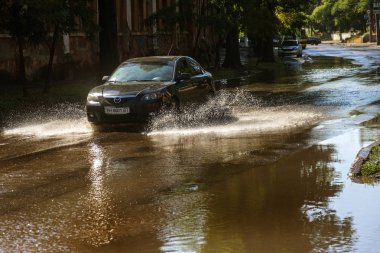 Odessa, Ukrayna -3 Temmuz 2018: yağmur fırtına tarafından neden olduğu sel sırasında su dolu bir yolda araba sürmek. Arabalar sokaklarda sel su üzerinde yüzer. Sıçramak üstünde belgili tanımlık makine. Büyük bir su birikintisi olan sular altında şehir yol