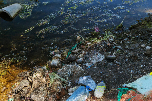Экологическая проблема. Мусор в воде. Пластиковые бутылки загрязняют природу. Бутылки и мусор в гавани морского порта Варны. Мусор в порту, в воде на стоянке небольших морских лодок
