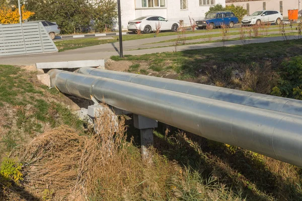 Modern Elevated Heat Pipes. Pipeline above ground, conducting heat to heat city. Urban heat line in metal insulation in residential quarter of city. Open laying on pillars. Municipal heat supply