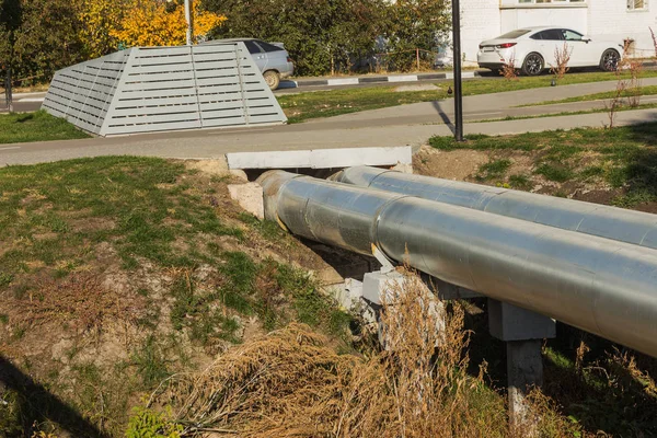 Modern Elevated Heat Pipes. Pipeline above ground, conducting heat to heat city. Urban heat line in metal insulation in residential quarter of city. Open laying on pillars. Municipal heat supply