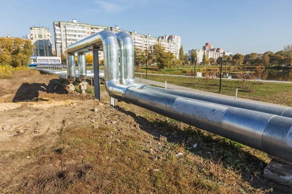 Modern Elevated Heat Pipes. Pipeline above ground, conducting heat to heat city. Urban heat line in metal insulation in residential quarter of city. Open laying on pillars. Municipal heat supply