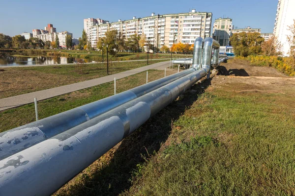 Modern Elevated Heat Pipes. Pipeline above ground, conducting heat to heat city. Urban heat line in metal insulation in residential quarter of city. Open laying on pillars. Municipal heat supply