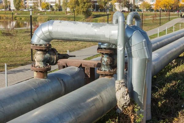 Modern Elevated Heat Pipes. Pipeline above ground, conducting heat to heat city. Urban heat line in metal insulation in residential quarter of city. Open laying on pillars. Municipal heat supply