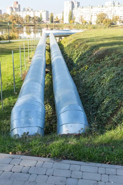 Modern Elevated Heat Pipes. Pipeline above ground, conducting heat to heat city. Urban heat line in metal insulation in residential quarter of city. Open laying on pillars. Municipal heat supply