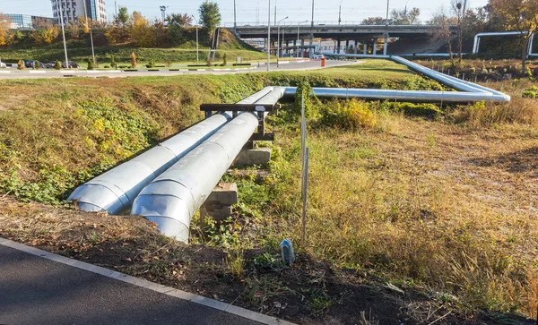 Modern Elevated Heat Pipes. Pipeline above ground, conducting heat to heat city. Urban heat line in metal insulation in residential quarter of city. Open laying on pillars. Municipal heat supply