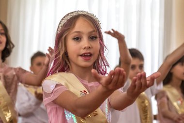 Odessa, Ukraine - May 31,2018: Children's musical group sing and dance on stage during graduation concert of elementary school. Children play. Emotional children's show on stage. Children's creativity clipart