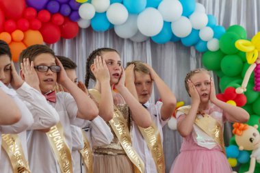 Odessa, Ukraine - May 31,2018: Children's musical group sing and dance on stage during graduation concert of elementary school. Children play. Emotional children's show on stage. Children's creativity clipart
