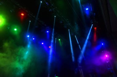 Sahne ışıkları. Karanlıkta birkaç projektör var. Gösteri sırasında sahnenin sahne ışıklarından gelen çok renkli ışık demetleri sahnenin dumanının içinde. Gece kulübü. Işıklar açık. Lazer gösterisi