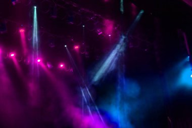 Sahne ışıkları. Karanlıkta birkaç projektör var. Gösteri sırasında sahnenin sahne ışıklarından gelen çok renkli ışık demetleri sahnenin dumanının içinde. Gece kulübü. Işıklar açık. Lazer gösterisi