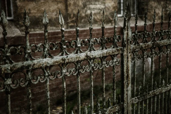 Old forged iron cast fence with sharp spears and cracked paint from time to time. White dirty abandoned fence that broke through the years of neglect. Stylized artwork vintage background for design