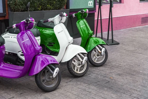 Motorcycles for pizza delivery, parked on the street, waiting for the order and delivery to the client. Mobile fast delivery of fresh hot pizza in the business part of the city