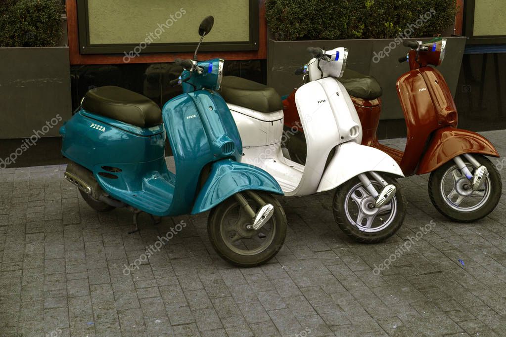 Motorcycles for pizza delivery, parked on the street, waiting for the order and delivery to the client. Mobile fast delivery of fresh hot pizza in the business part of the city
