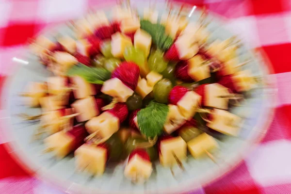 Bright abstract dish background with grapes, strawberries and cheese. Unusual bright abstract background of cheese with grapes on sword-toothpick for restaurant. Selective not deep focus, blur