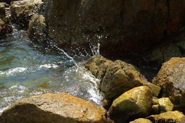 Güzel deniz dalgaları kayalık sahil buzlu ayrılır. Aydınlık yatay görüntüleme biçimi reklam yaz seyahat, geri kalanı için bir arka plan üzerinde deniz, okyanus. Kayanın üzerinde çökmesini dalgalar deniz manzaralı