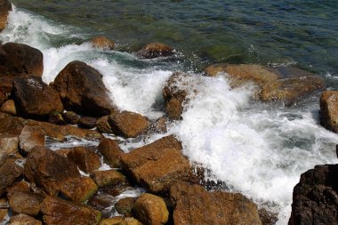 Güzel deniz dalgaları kayalık sahil buzlu ayrılır. Aydınlık yatay görüntüleme biçimi reklam yaz seyahat, geri kalanı için bir arka plan üzerinde deniz, okyanus. Kayanın üzerinde çökmesini dalgalar deniz manzaralı