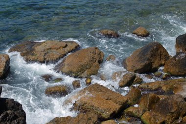Güzel deniz dalgaları kayalık sahil buzlu ayrılır. Aydınlık yatay görüntüleme biçimi reklam yaz seyahat, geri kalanı için bir arka plan üzerinde deniz, okyanus. Kayanın üzerinde çökmesini dalgalar deniz manzaralı