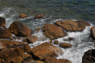 Güzel deniz dalgaları kayalık sahil buzlu ayrılır. Aydınlık yatay görüntüleme biçimi reklam yaz seyahat, geri kalanı için bir arka plan üzerinde deniz, okyanus. Kayanın üzerinde çökmesini dalgalar deniz manzaralı