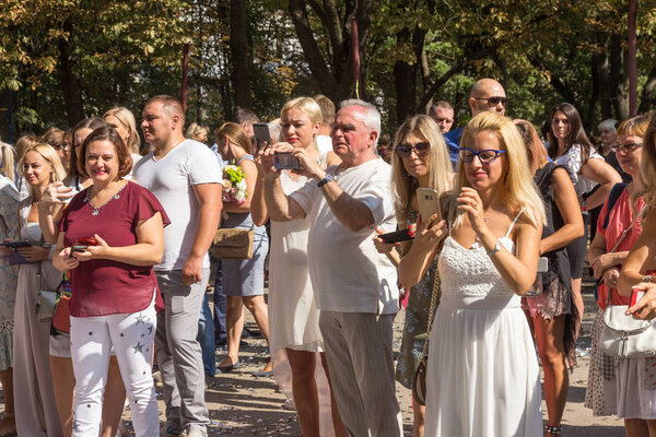 Odessa, Ukraine - September 1, 2018: Happy parents, mothers take pictures of their smart children on the phone during the festival of knowledge -1 September, Knowledge Day