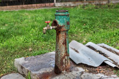 Retro Çeşme içme suyu el pompası ile kırık ve kabaca yükseltilmiş. Modern bir vinç ile içme suyu musluk suyu ısıtıcı