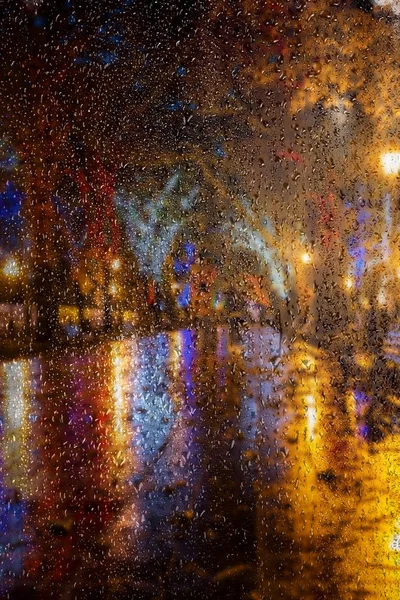 Blur night cityscape. The ancient center of the city at night after rain. Night urban street with bright colored lights of street cafes and moving cars. Motion blur, soft focus, stylization