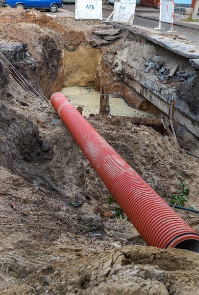 Dug deep trench utilities engineering urban systems. Alarm system of urban sanitation and heating. Trench is filled with rusty dirty water erupted from pipeline. Repair work underground utilities