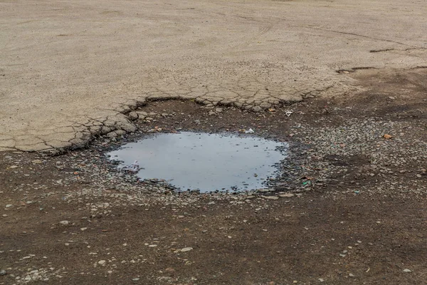 Very bad paved road. Cracks in the pavement, potholes. Very poor condition of local asphalt road after a low-quality patching