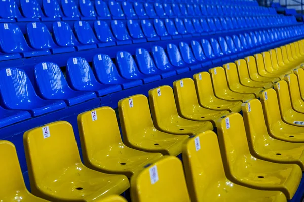 Blank old plastic chairs in the gym. Number of empty seats in a small sports complex. New Rows of plastic seats for fans. Shallow depth of field perspective, soft focus