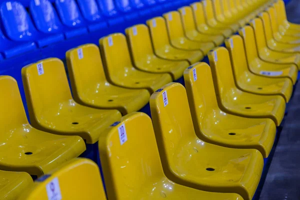 Blank old plastic chairs in the gym. Number of empty seats in a small sports complex. New Rows of plastic seats for fans. Shallow depth of field perspective, soft focus