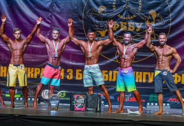 Odessa, Ukrayna -23 Ekim 2016: sporcular erkekler vücut geliştirme ve fitness kategori fitness ve vücut geliştirme modeli üzerinde Şampiyonası Ukrayna katılmak. Sahne Alanı'nda büyük kas erkeklerle güzel atletik rakam