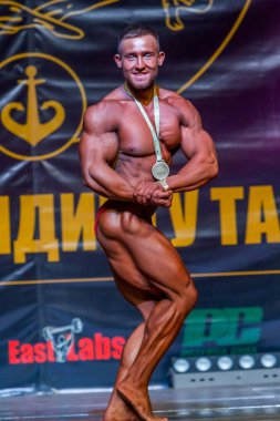 Odessa, Ukrayna -23 Ekim 2016: sporcular erkekler vücut geliştirme ve fitness kategori fitness ve vücut geliştirme modeli üzerinde Şampiyonası Ukrayna katılmak. Sahne Alanı'nda büyük kas erkeklerle güzel atletik rakam