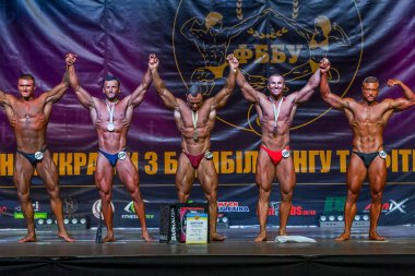 Odessa, Ukrayna -23 Ekim 2016: sporcular erkekler vücut geliştirme ve fitness kategori fitness ve vücut geliştirme modeli üzerinde Şampiyonası Ukrayna katılmak. Sahne Alanı'nda büyük kas erkeklerle güzel atletik rakam