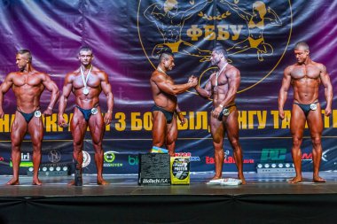 Odessa, Ukrayna -23 Ekim 2016: sporcular erkekler vücut geliştirme ve fitness kategori fitness ve vücut geliştirme modeli üzerinde Şampiyonası Ukrayna katılmak. Sahne Alanı'nda büyük kas erkeklerle güzel atletik rakam
