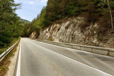 Dolambaçlı bir dağ yolu. İki yönlü yol dağlarda. Kayalık yamaçlarda taş yakınlarındaki dağlık bir alanda asfalt karayolu