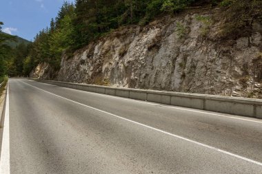 Dolambaçlı bir dağ yolu. İki yönlü yol dağlarda. Kayalık yamaçlarda taş yakınlarındaki dağlık bir alanda asfalt karayolu