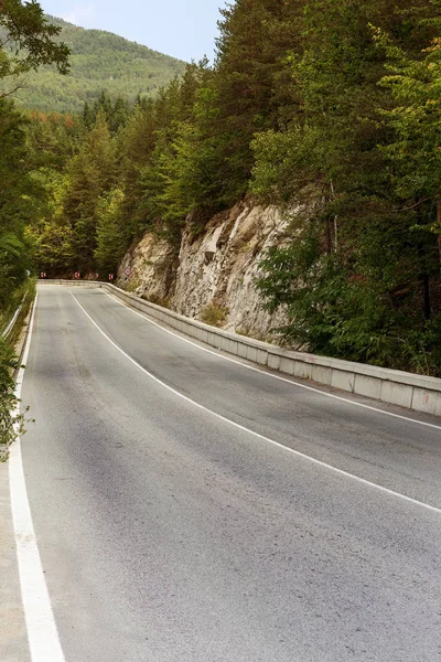 A winding mountain road. Two-way road in the mountains. Paved highway in a mountainous area near the rocky slopes of stone