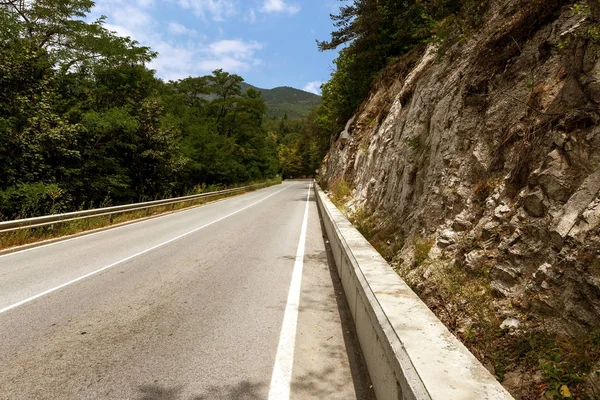 A winding mountain road. Two-way road in the mountains. Paved highway in a mountainous area near the rocky slopes of stone